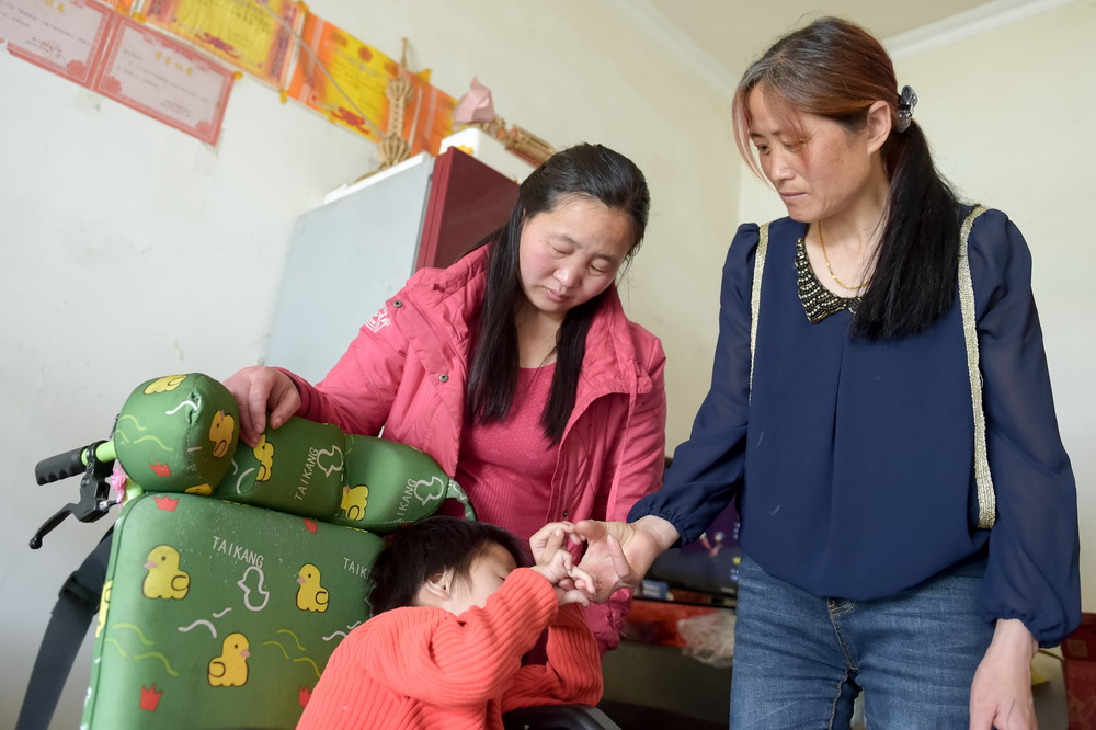 安徽潜山县水吼镇三里村党支部书记汪义琴（右）在三里村走访因病致贫的贫困户（5月6日摄）。