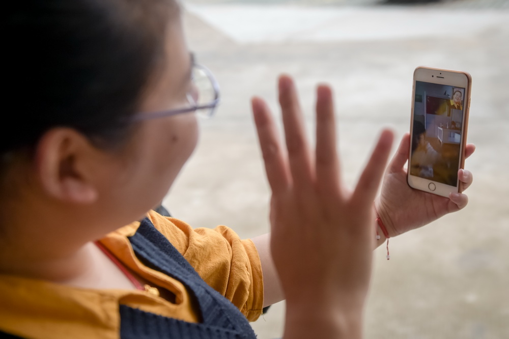 安徽潜山县官庄镇扶贫办副主任郑黎明在平峰村与女儿视频之后挥手再见（5月7日摄）。