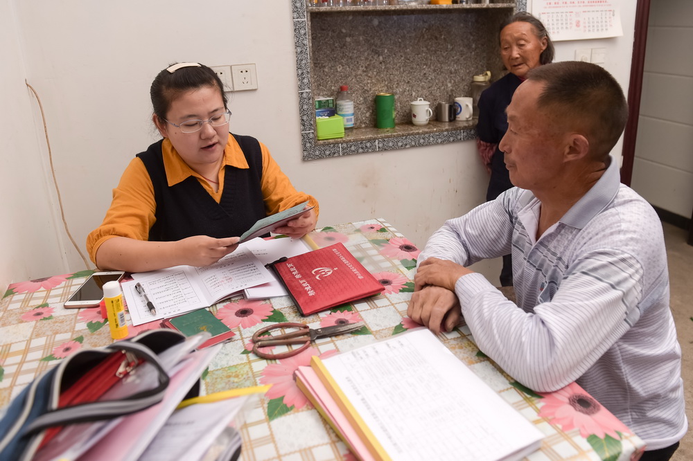 安徽潜山县官庄镇扶贫办副主任郑黎明（左）在平峰村走访贫困户（5月7日摄）。