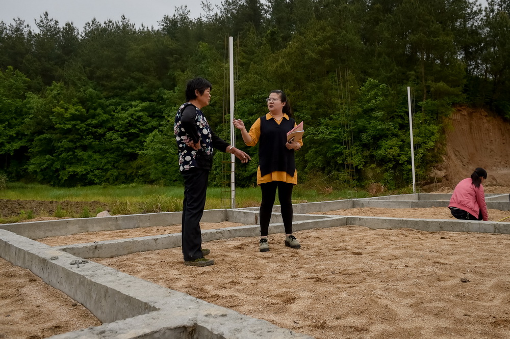 安徽潜山县官庄镇扶贫办副主任郑黎明（中）在平峰村走访实施了易地扶贫搬迁的贫困户（5月7日摄）。