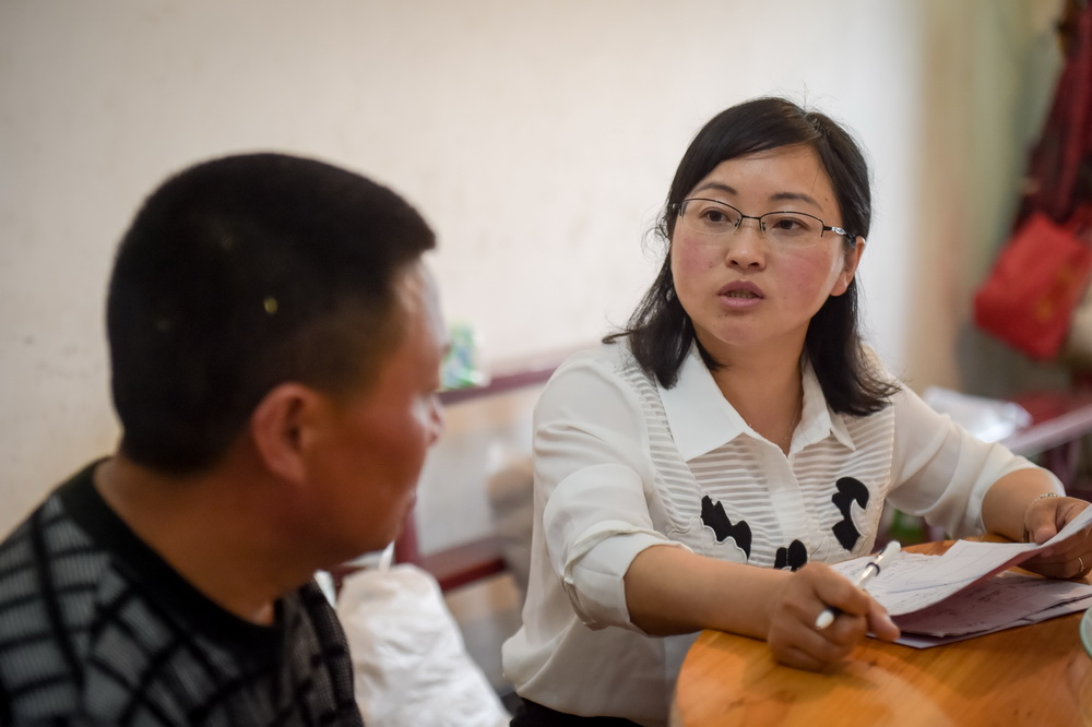 安徽潜山县巍岭乡杨河村第一书记、驻村扶贫工作队长刘和平（右）在杨河村走访2016年刚刚脱贫的村民（5月11日摄）。