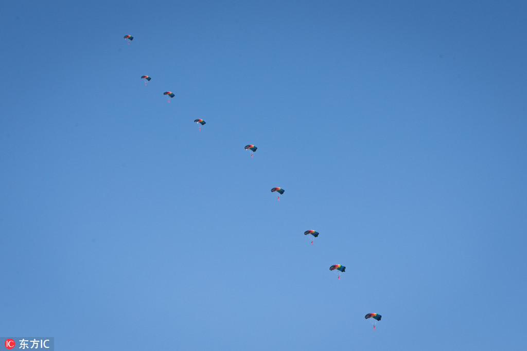 武汉开发区汉南通航机场上空，随着一架运-12飞过，天空中此地展开一朵朵降落伞，现场玩起“仙女散花”，“世界飞行者大会”跳伞运动员抵达现场并进行了试跳。