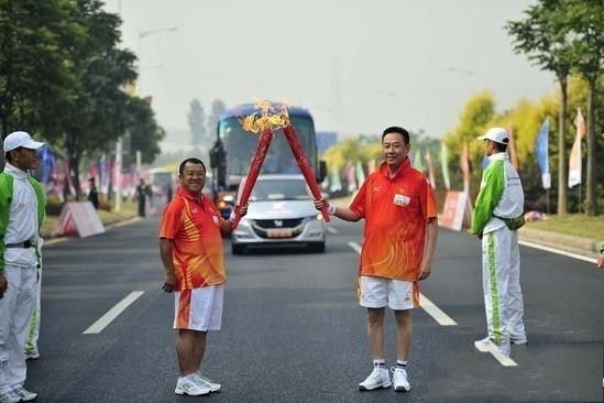 16届亚洲运动会火炬传递活动在广州大学城举行。图为火炬手曾志伟和戚凡科。 图片来源:网络