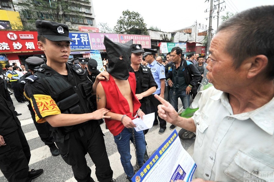 贵阳盗抢疑犯街头带脚镣指认现场 民众围拍