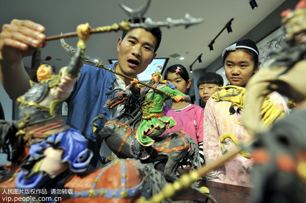 5月14日，山东省郯城县面塑传承人韩红元（右二）在“非遗”传承大课上向孩子们讲解面塑历史人物的捏制技艺。