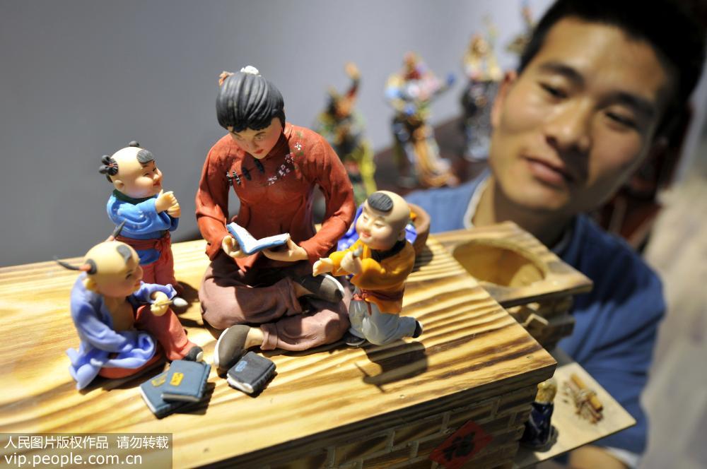 5月14日，山东省郯城县面塑传承人韩红元展示创作捏制的面塑作品《传承》。